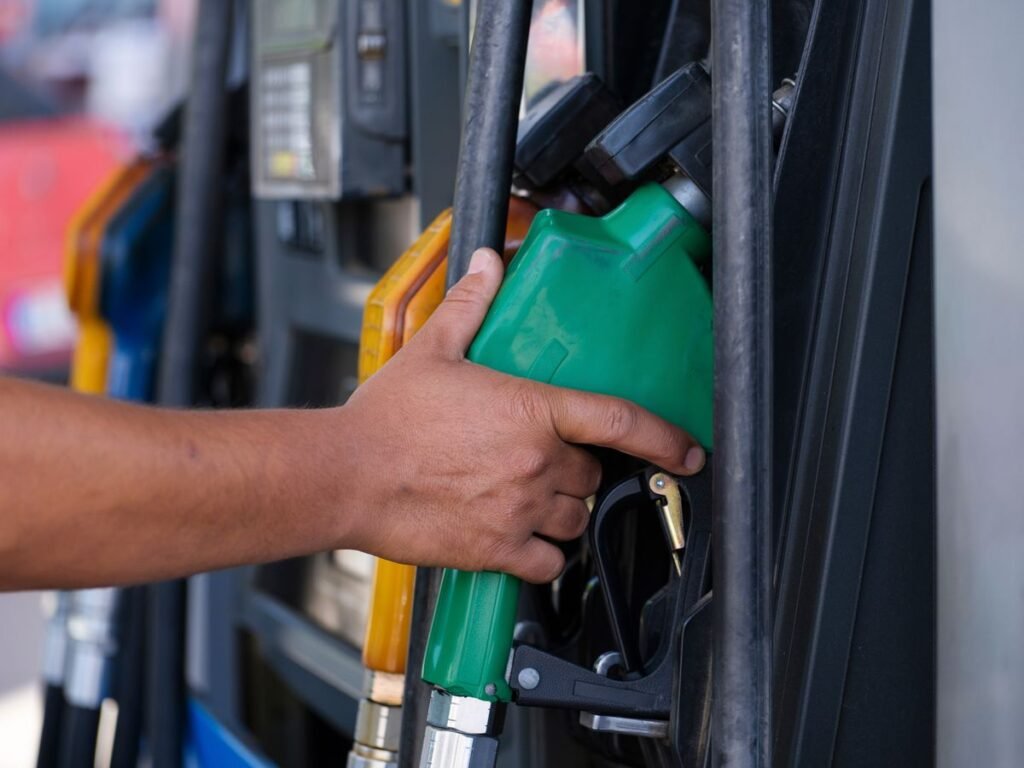 Close up of a hand holding a green fuel nozzle at a gas pump