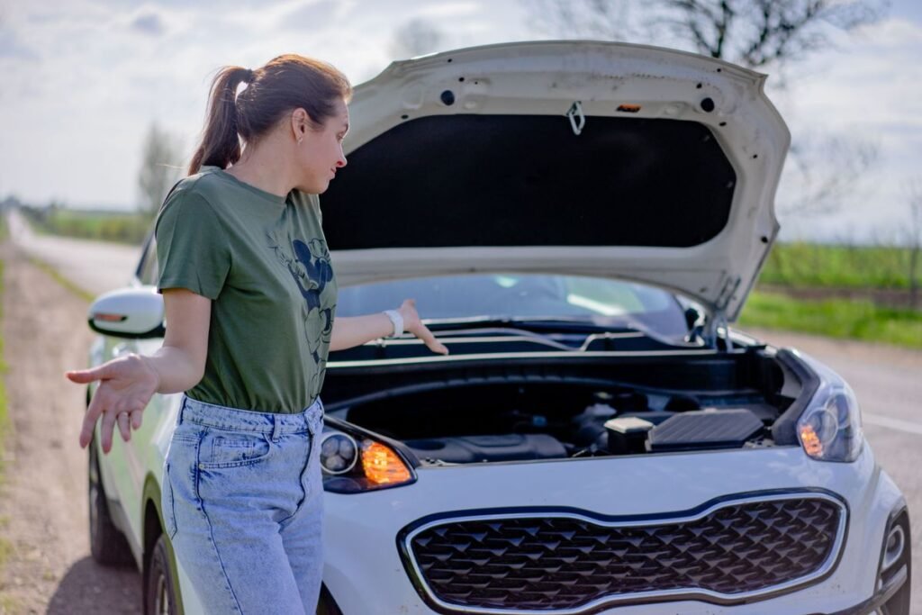Woman looking puzzled at her broken car with the hood open on a rural road