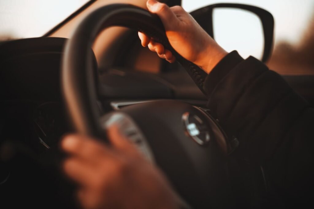 Close up of hands gripping a steering wheel in warm light