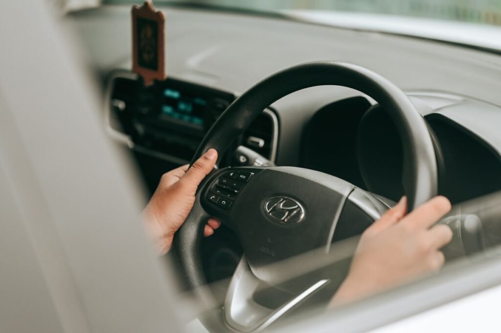Close up of hands holding a steering wheel inside a car