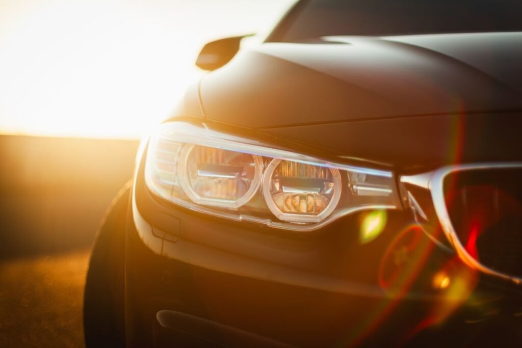 Sunlit close up of a sleek modern car headlight with lens flare at sunset