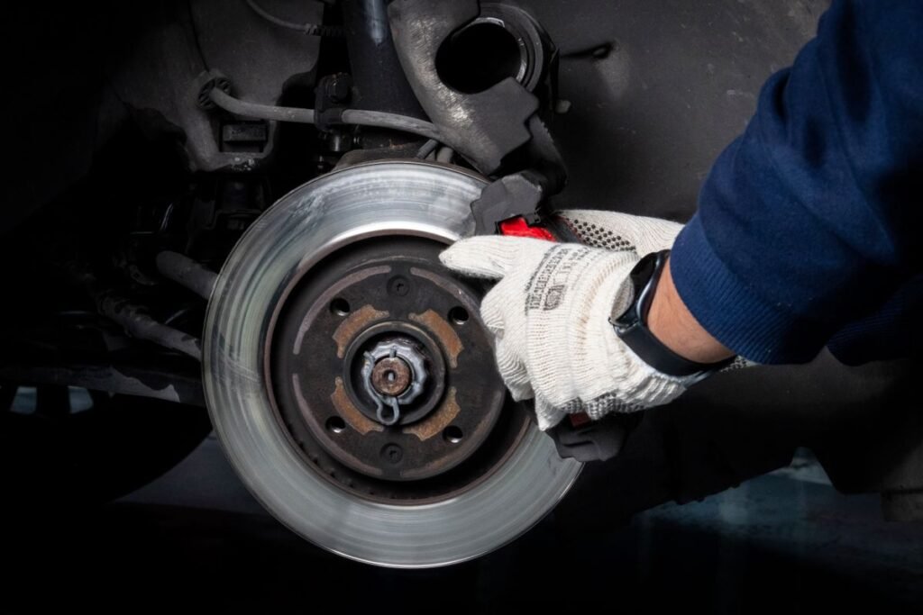 Mechanic working on a car brake disc and caliper in a workshop