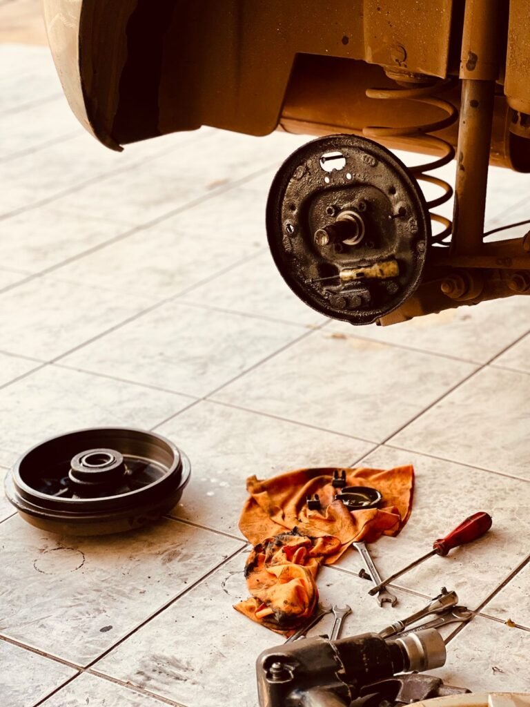 Close up of a dismantled car brake rotor and tools laid out on a garage floor during brake service
