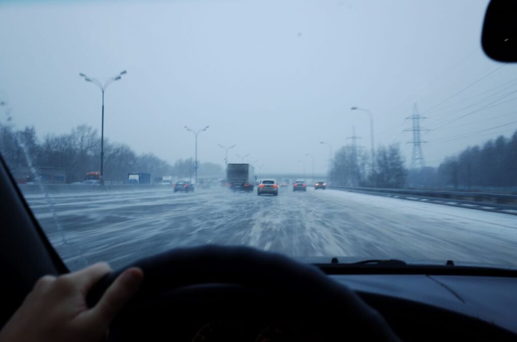 Driving on an icy winter road at dusk with snowy traffic