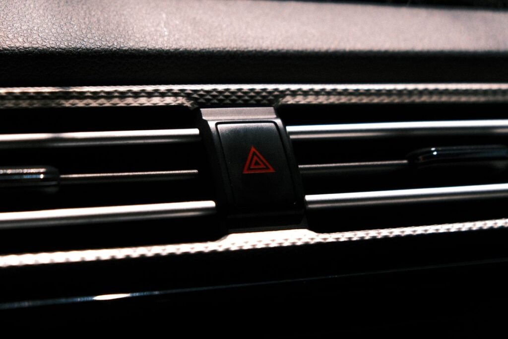 Close up of the red triangle hazard light button on a dark car dashboard