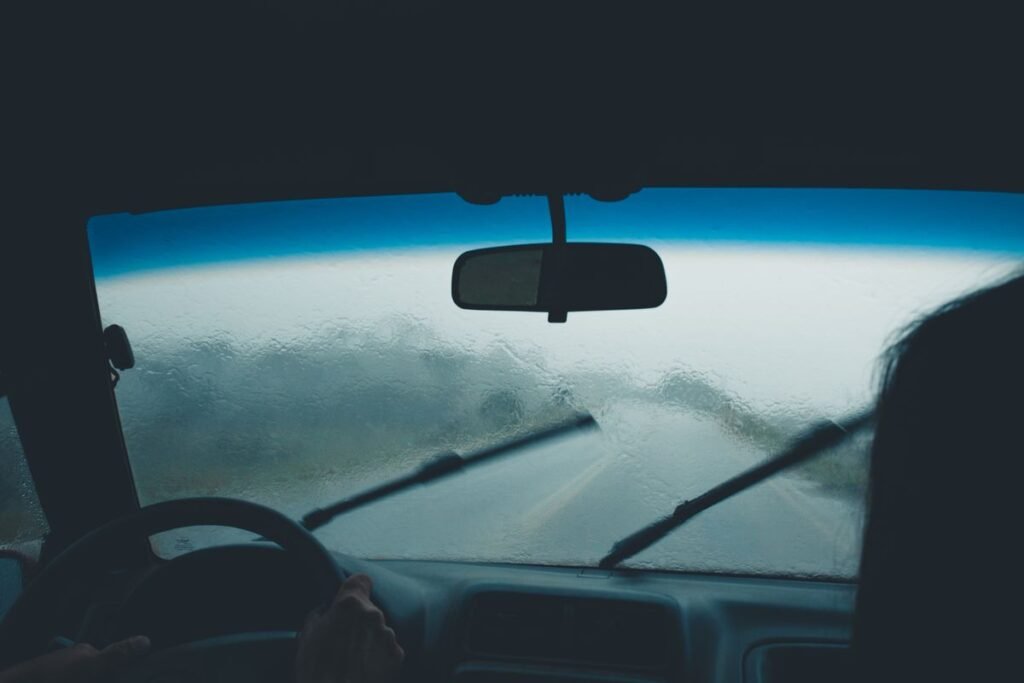 View from inside a car on a rainy day, droplets on the windshield and wipers in motion