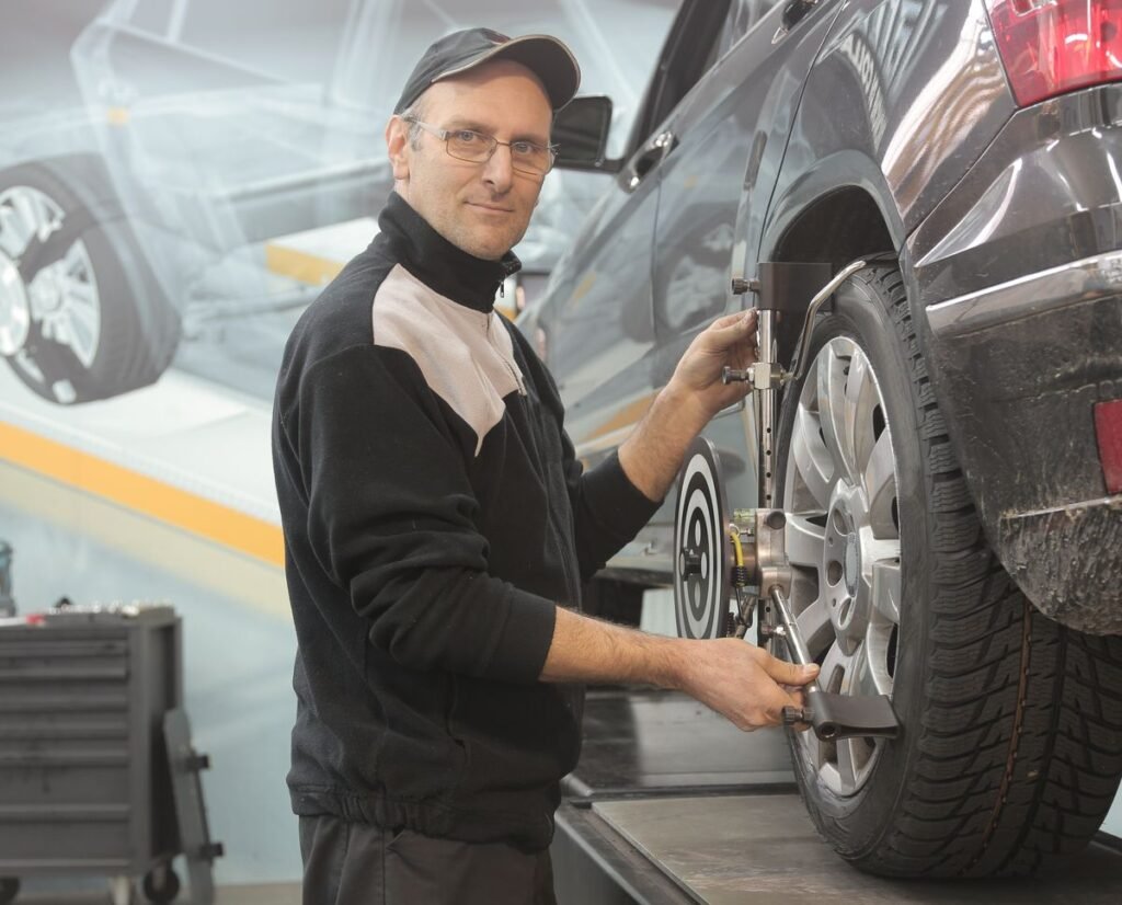 Mechanic performing a wheel alignment on a car in a professional garage