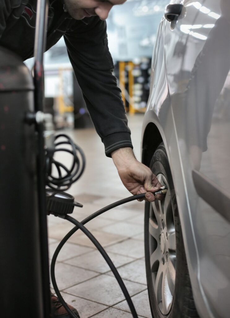 Mechanic adjusting the tire pressure of a vehicle in an indoor automotive service center