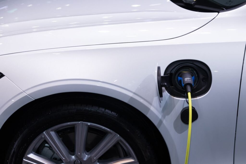 White electric car plugged in for charging, close up view of the charging port