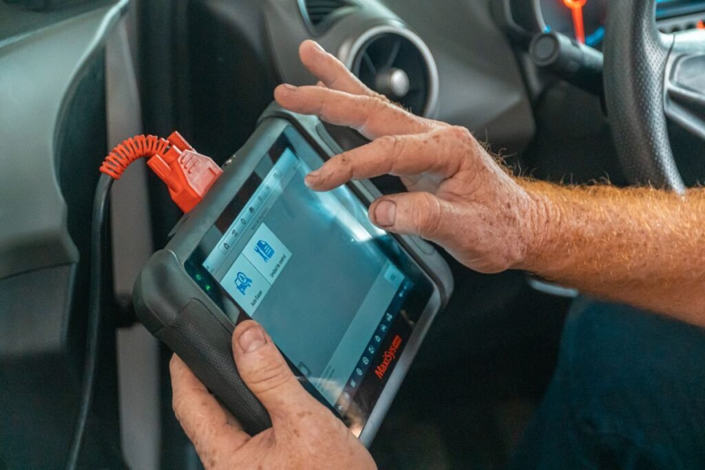 Mechanic using a diagnostic tool inside a car to check for engine issues
