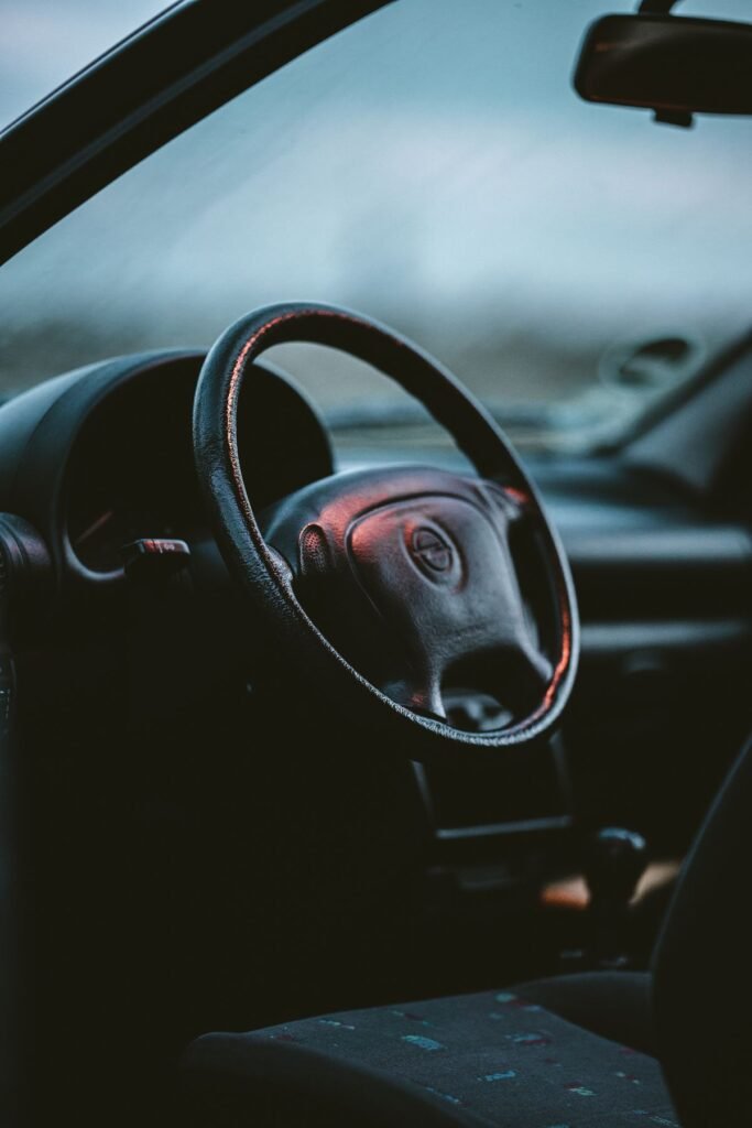 Detailed shot of a modern car steering wheel and dashboard in soft light, the airbag sits in the wheel hub