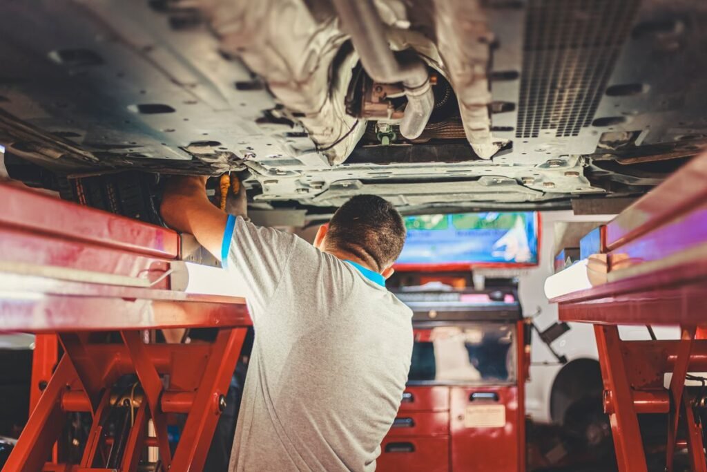 Mechanic working under a lifted car in a repair shop