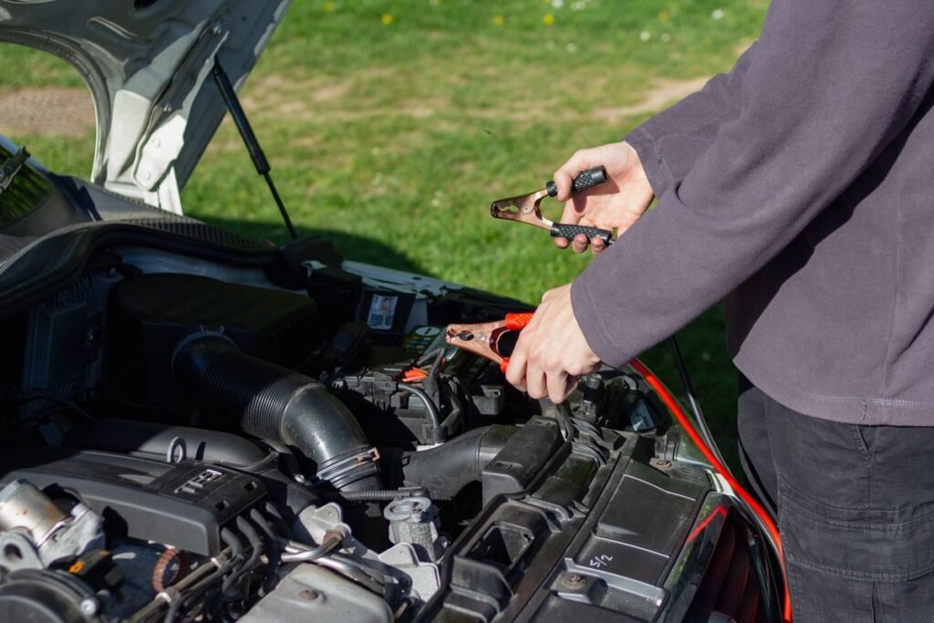 Close up of a mechanic using jumper cables to jump start a car battery outdoors