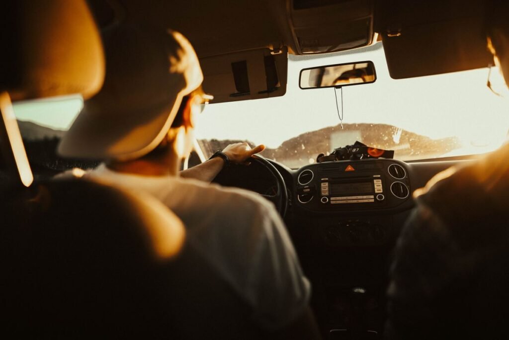 Man holding the steering wheel while driving at sunset