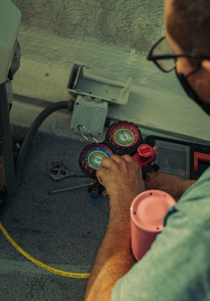 Technician adjusting a refrigerant manifold gauge for air conditioning service