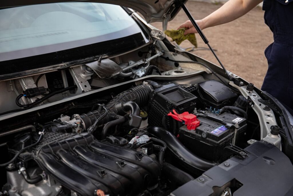 Mechanic inspecting a car engine bay and battery during routine maintenance