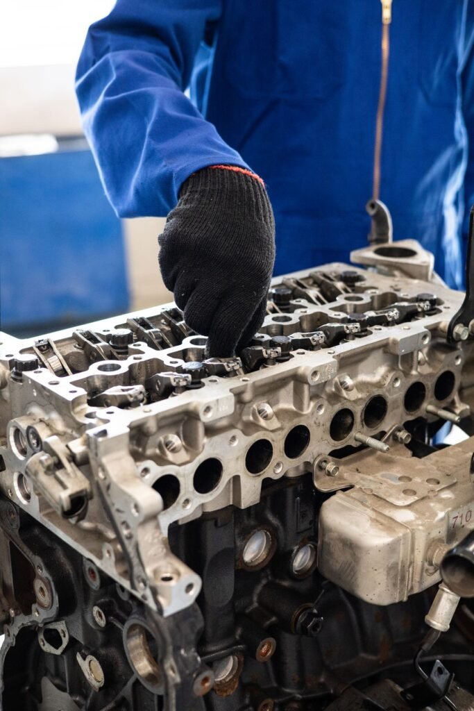 Mechanic in gloves inspecting a car engine cylinder head in a workshop